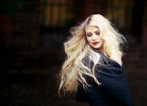 blonde girl wearing black against black background
