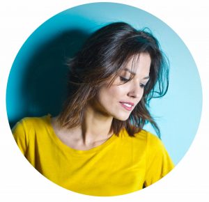 brunette woman in yellow t-shirt against blue background
