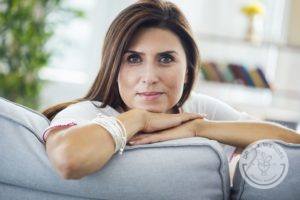 brunette woman leaning on couch with dr. jj wendel logo