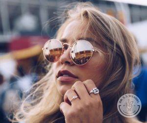 blonde woman in sunglasses wearing rings looking to side