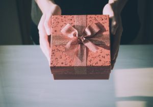 woman's hands holding red wrapped gift box
