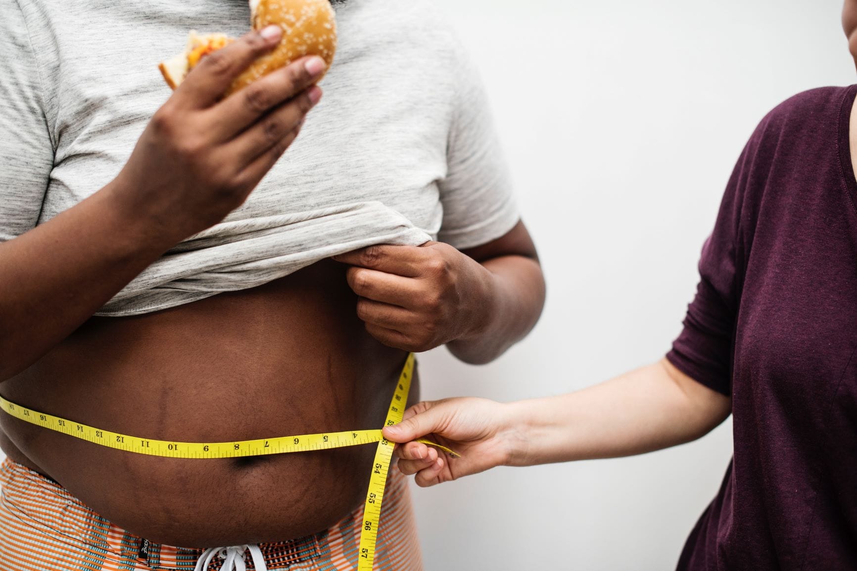 photo of person eating while a doctor measures their stomach with a tape measure