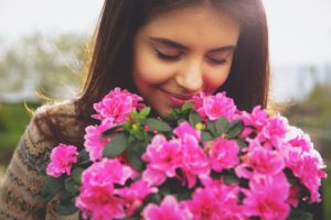 Young brunette woman smelling bouquet of pink flowers