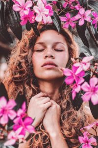 Woman with curly hair surrounded by pink flowers