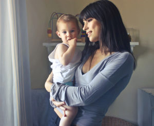 Young, caucasian women with brunette hair holding baby