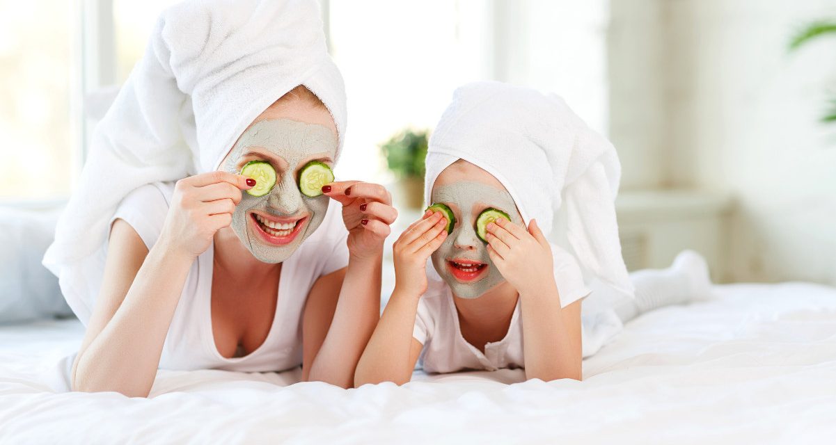 Mother and child laying on the bed with cucumbers over their eyes
