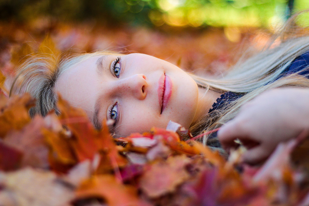 Close up of woman's face laying in fall leaves