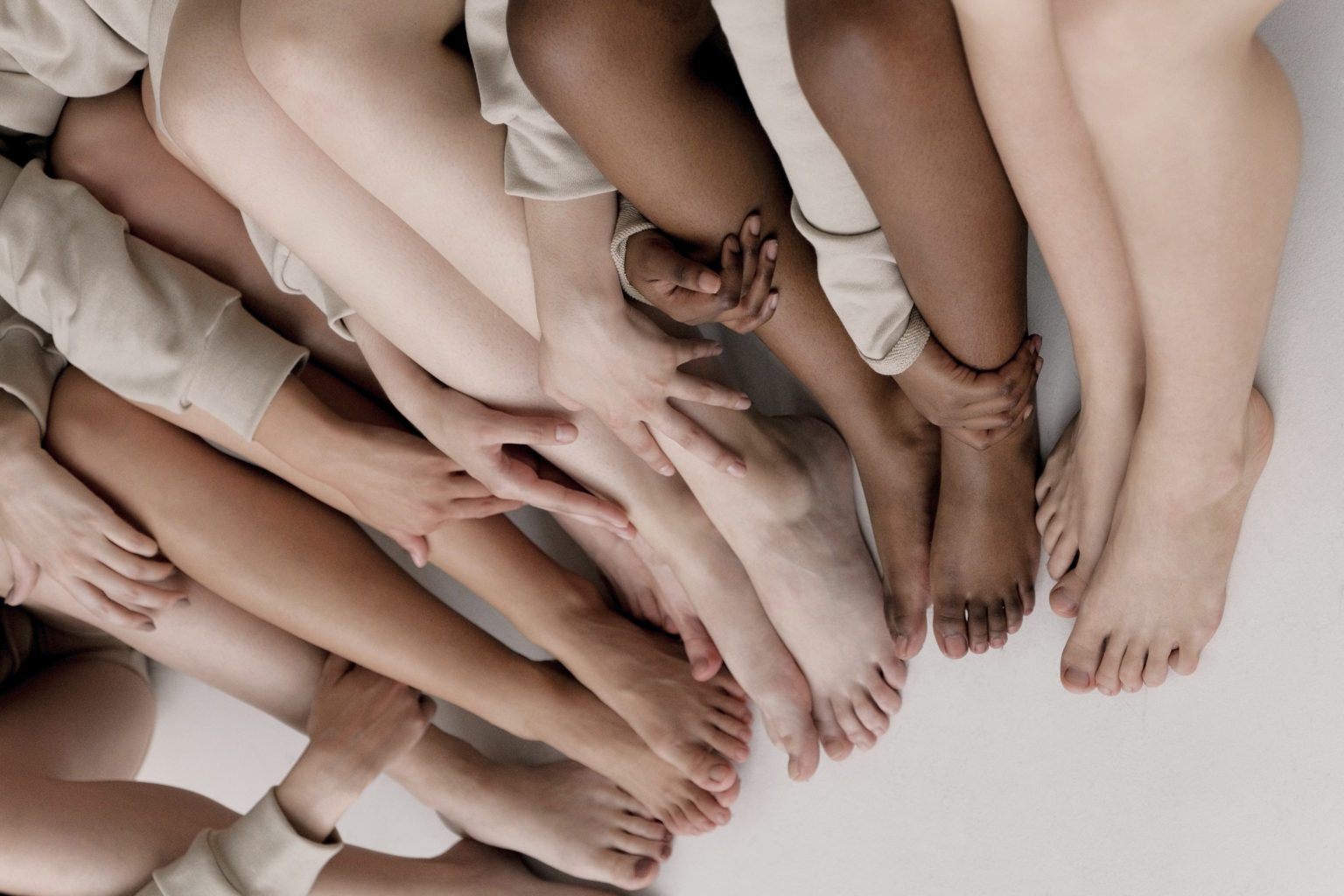 5 women sitting down with bare legs and feet