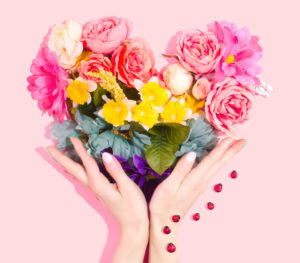 Hands holding heart shaped bouqet of flowers