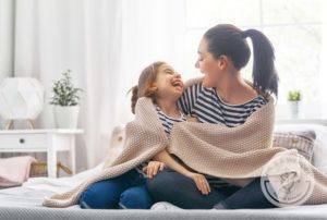 Mom and daughter hugging under a blanket