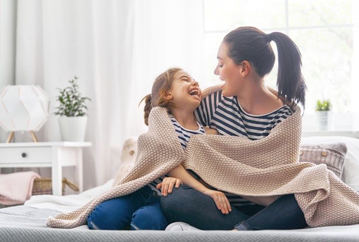 Mom and daughter hugging under a blanket
