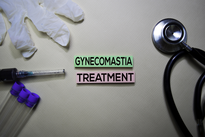 stethoscope and medical glove next to pink and green label reading "gynecomastia treatment" in black letters