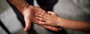 Child's hand facing down on top of father's hand facing up