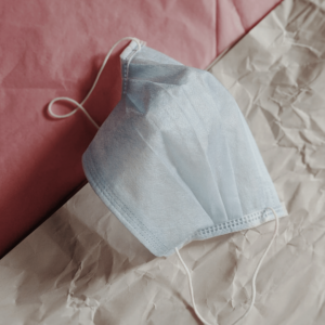 Medical face mask laying on pink and cream paper