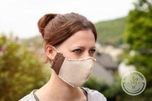 brunette woman wearing beige face mask outside