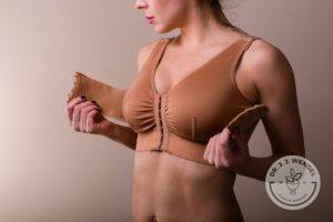 woman wearing tan medical bra after breast augmentation