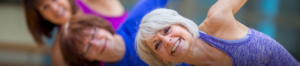 three women stretching and smiling in a fitness class