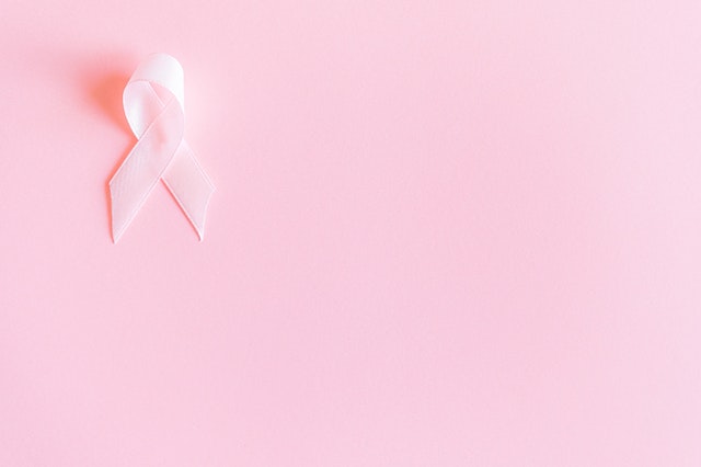 Pink breast cancer ribbon with a pink background