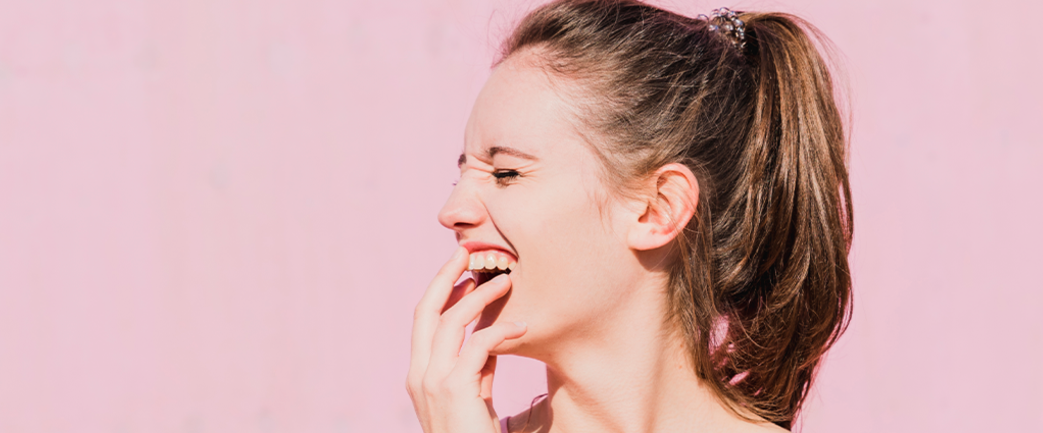 young smiling woman in front of a light pink background