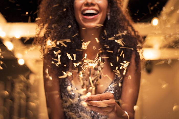 smiling african american woman in gold dress holding a gold sparkler