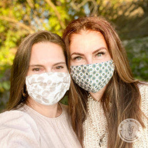 Two young brunette women smiling wearing face masks