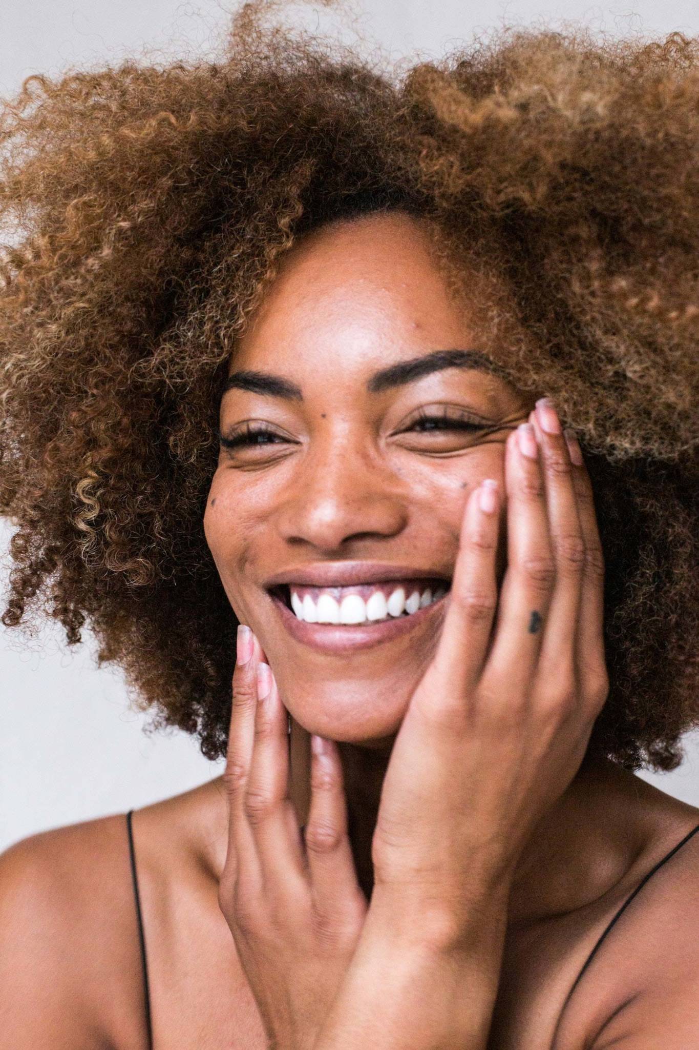 Smiling African American woman with her hands on her face