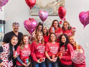 Team photo of Dr. J. J. Wendel Plastic Surgery wearing red t-shirts with pink and red balloons in the background