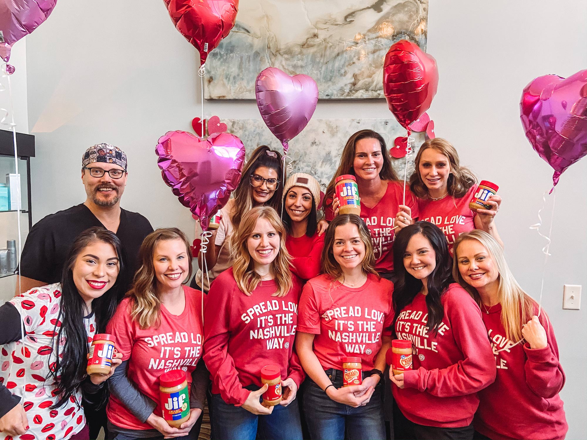 Team photo of Dr. J. J. Wendel Plastic Surgery wearing red t-shirts with pink and red balloons in the background