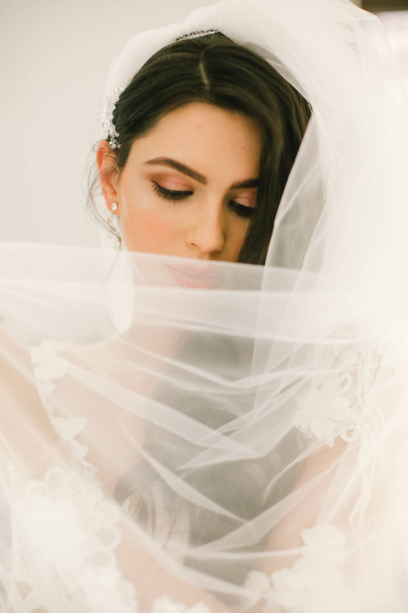 headshot of bride wearing veil and pulling it across her face