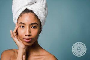 woman of color wearing towel in hair and touching face