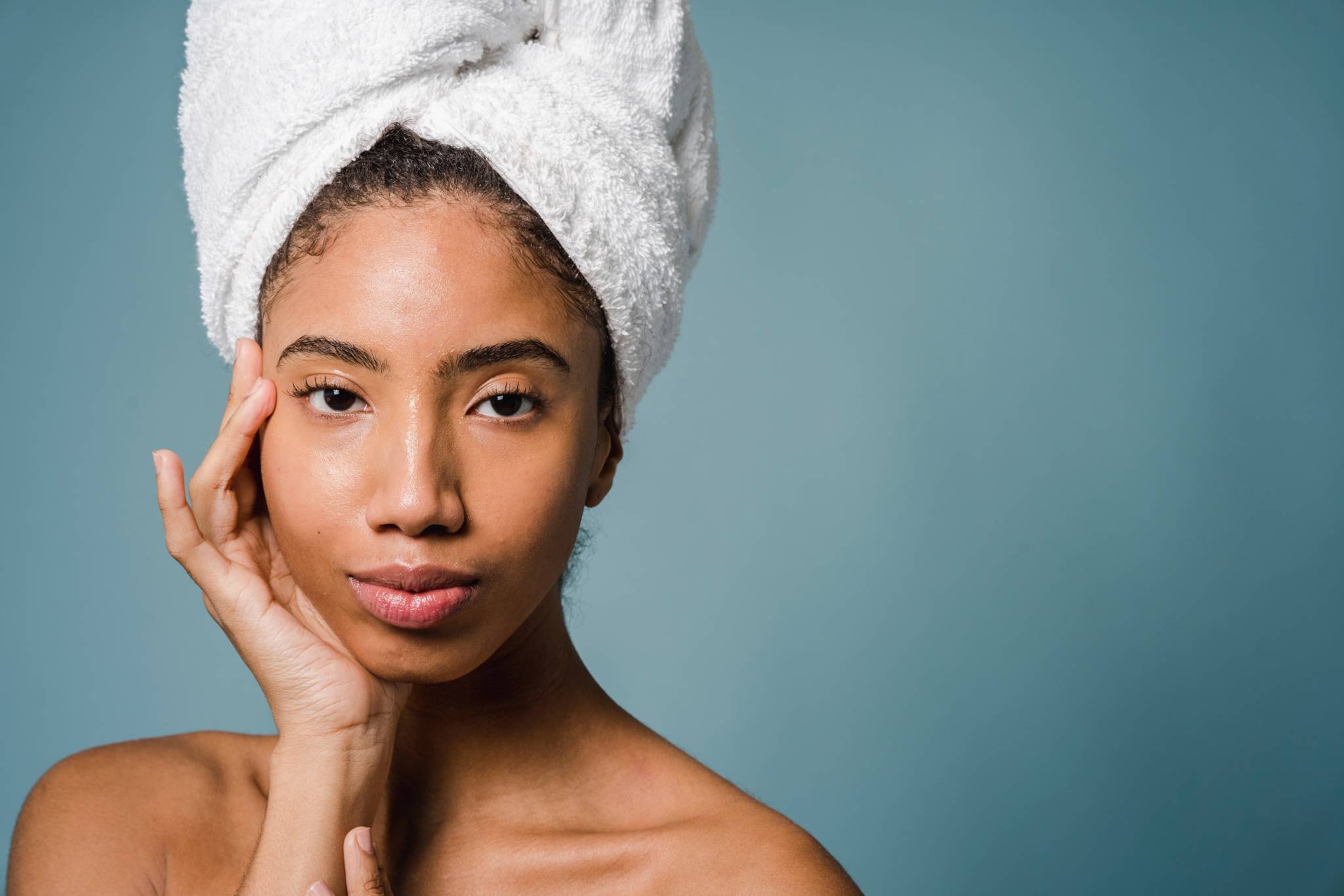 woman of color wearing towel in hair and touching face