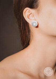 brunette woman's neck and jawline, wearing a pearl earrinng