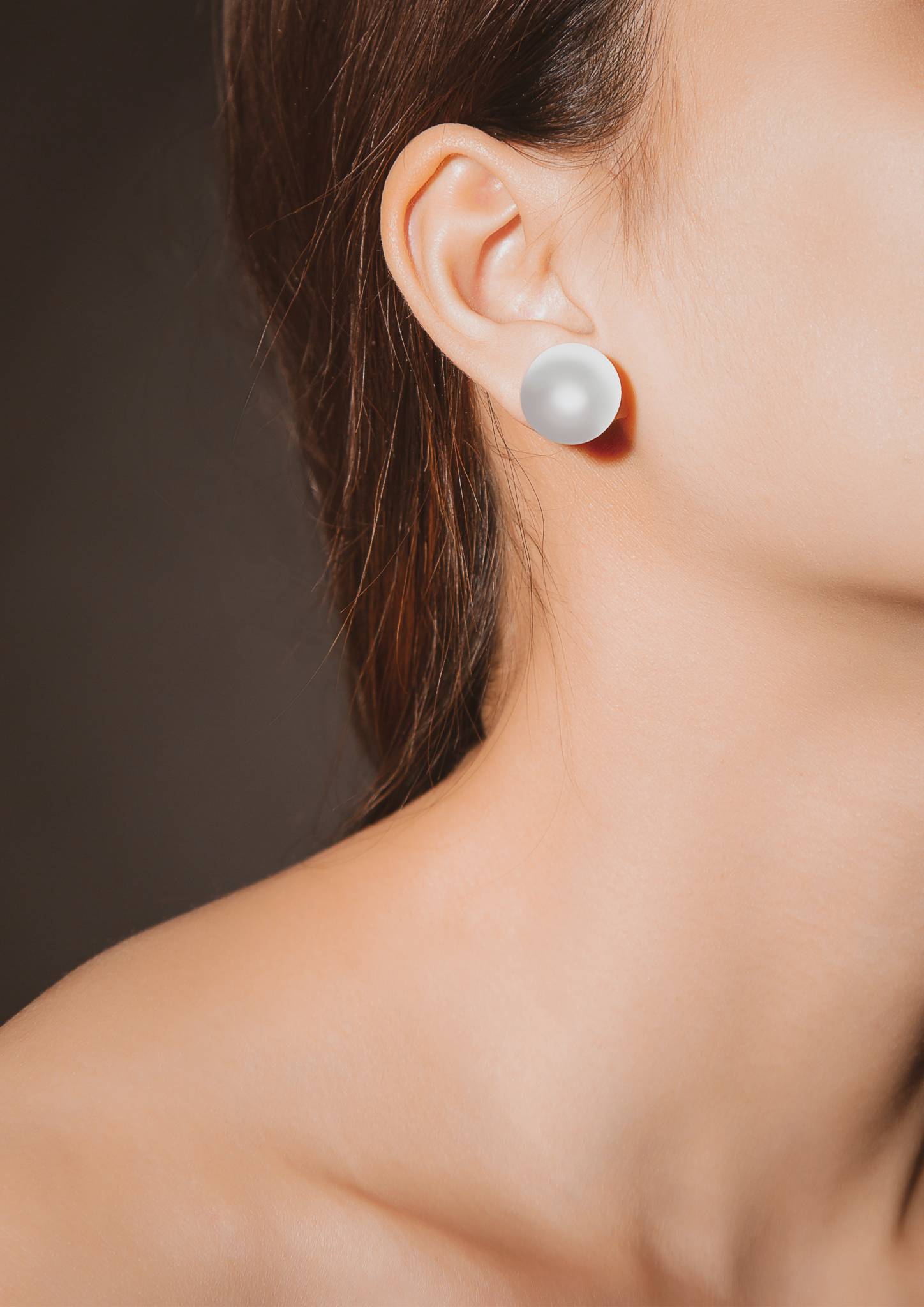 brunette woman's neck and jawline, wearing a pearl earrinng