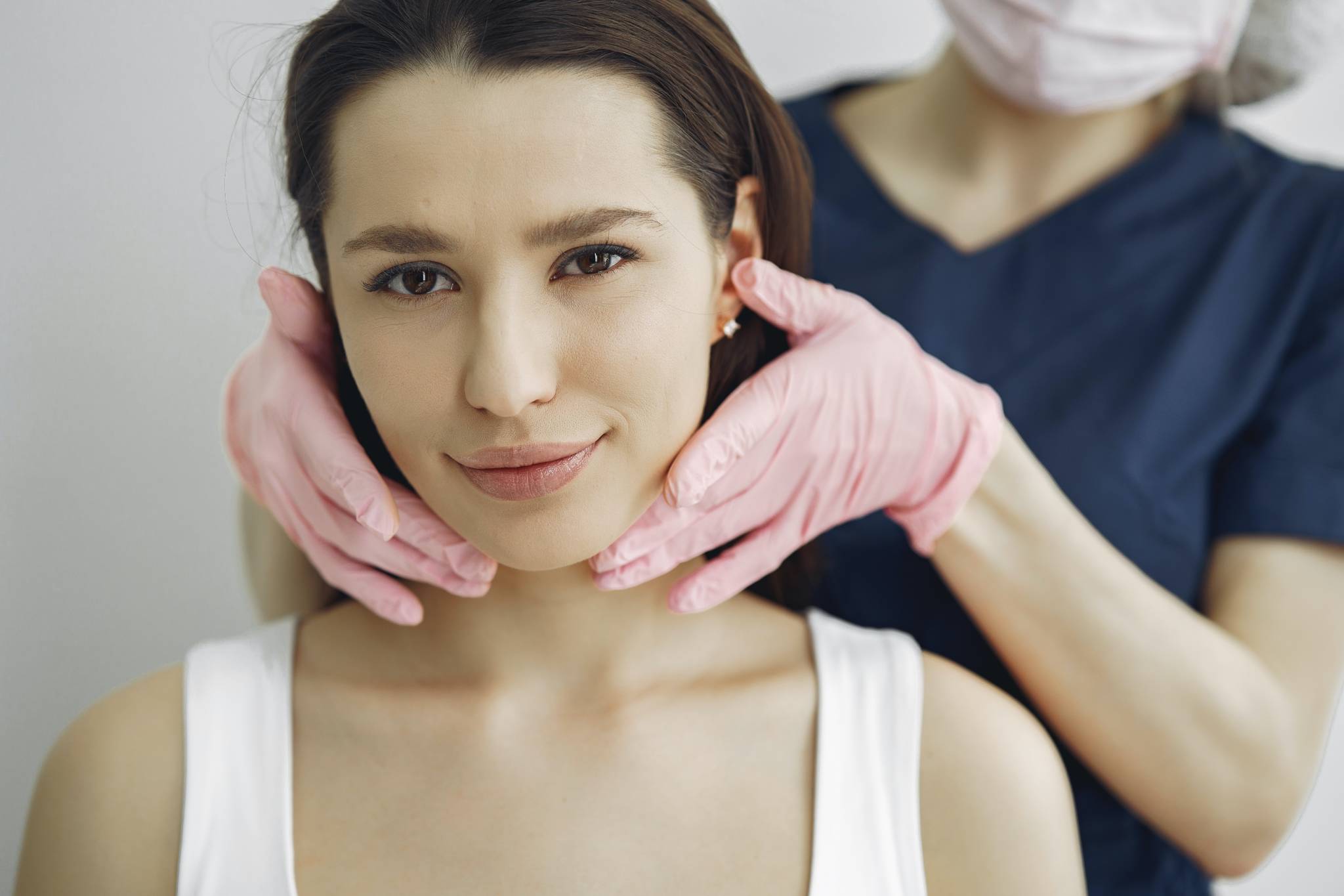 woman staring at camera while doctor with gloves on touches her face