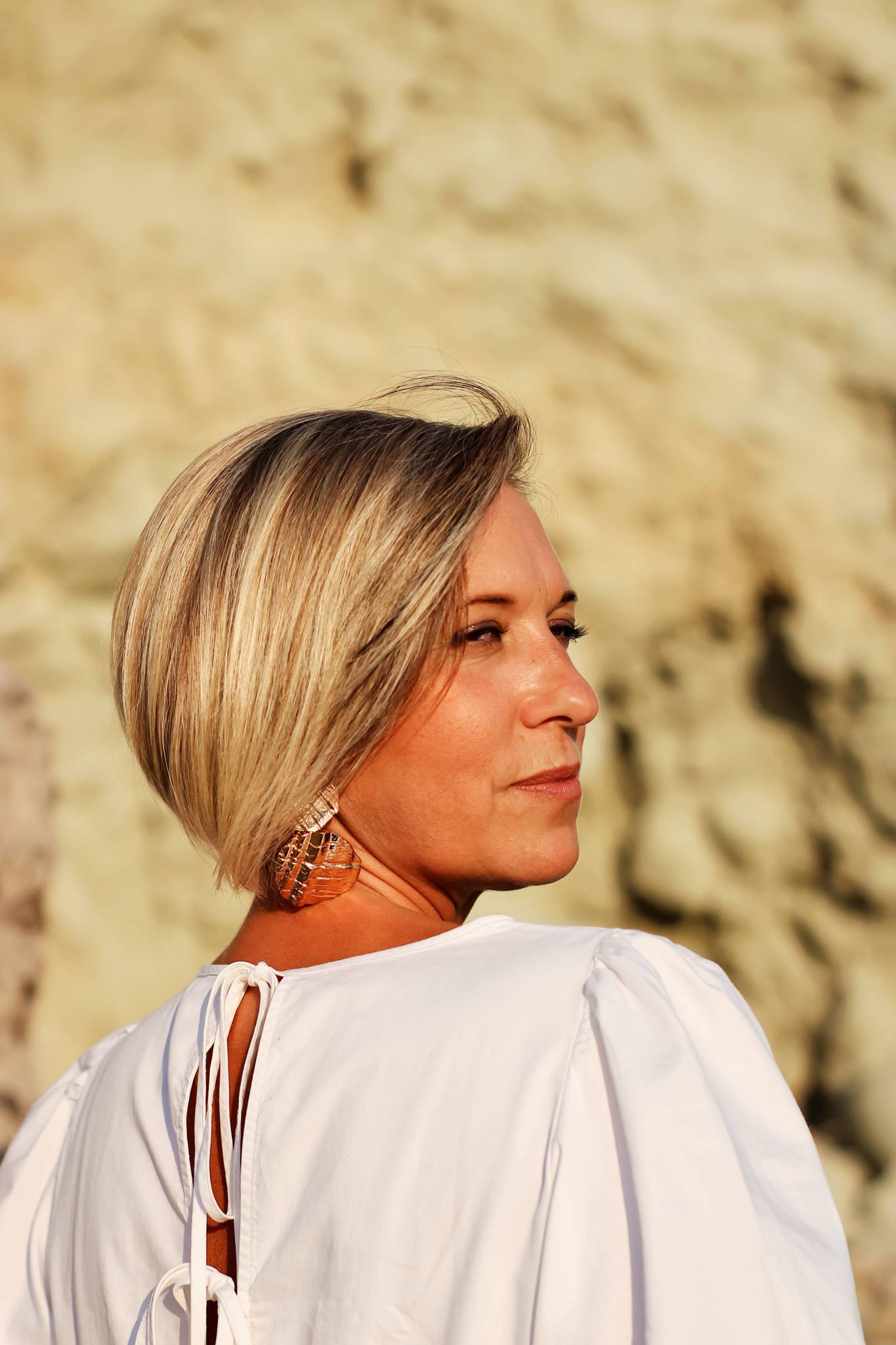 woman outside in white blouse with back to camera and face looking back at camera