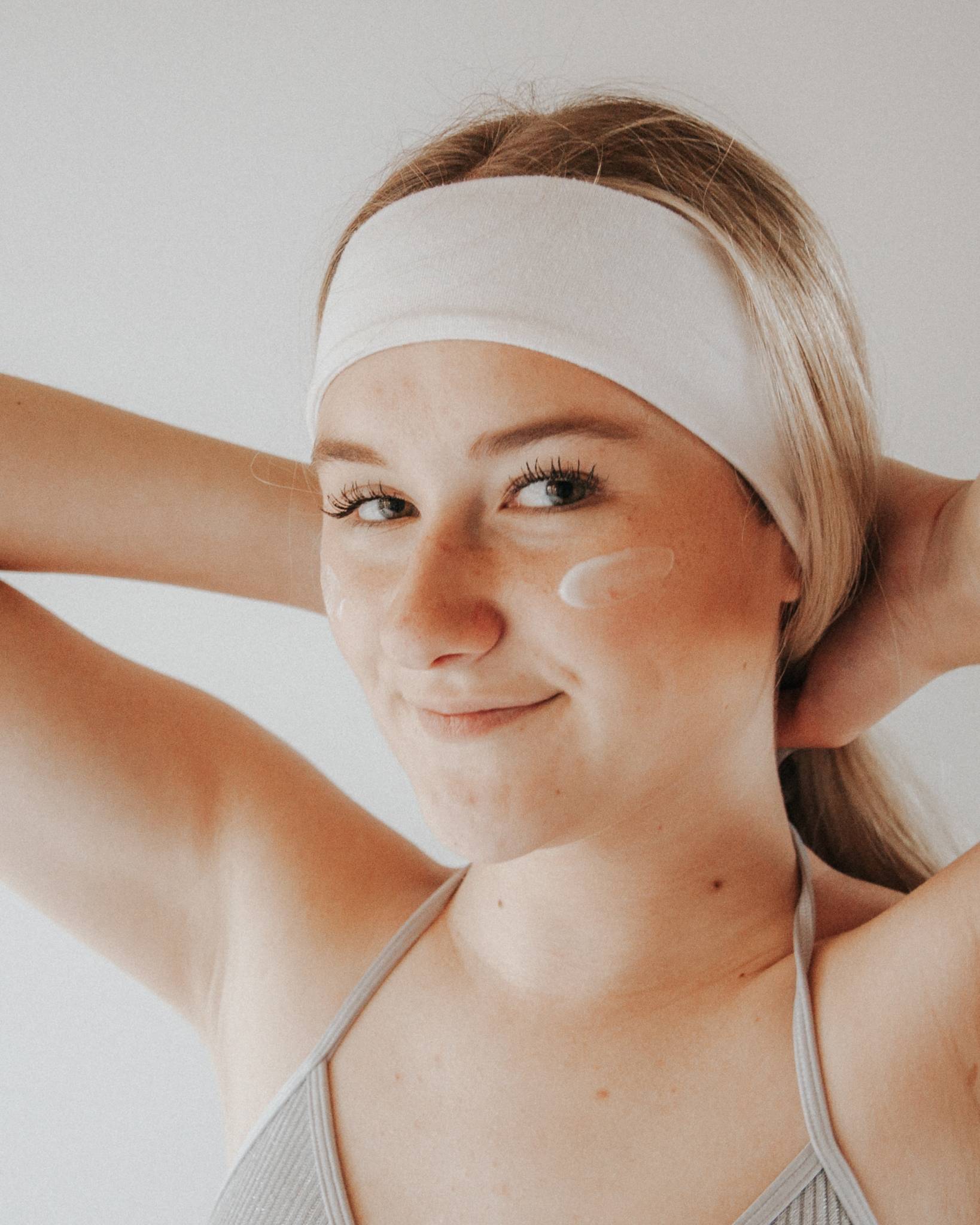 woman wearing hairband with moisturizer on face