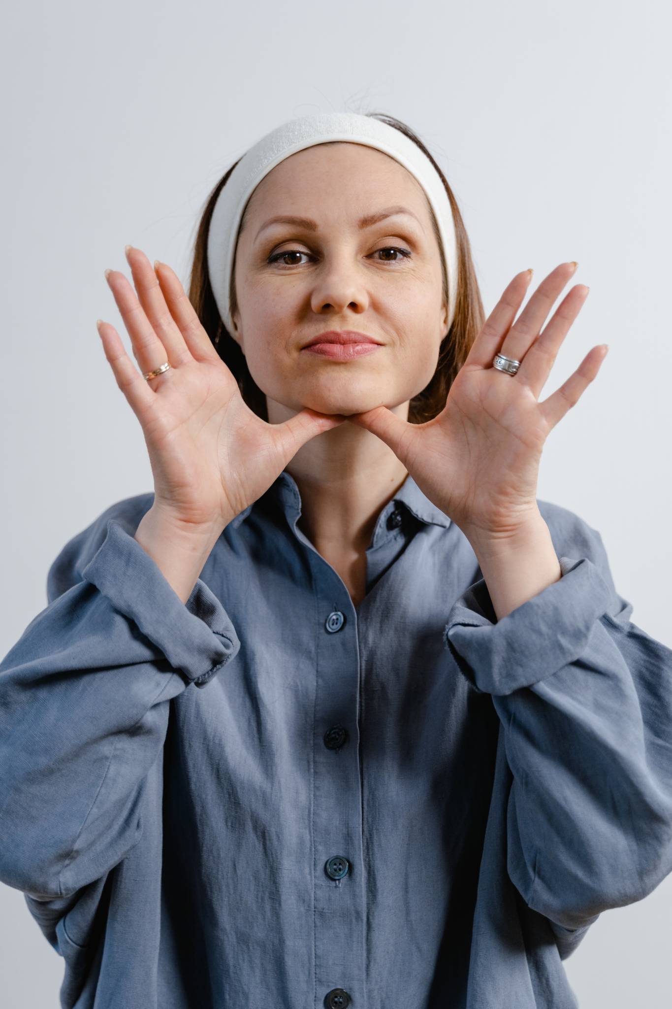 woman in oversized shirt touching her chin with palms up