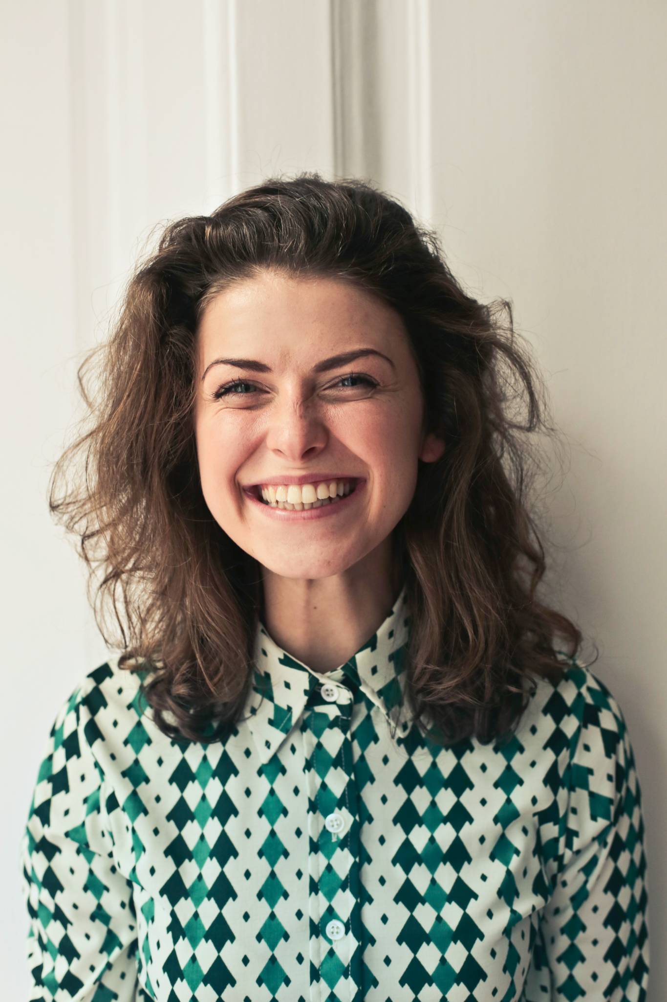 woman with curly hair in patterned shirt grinning