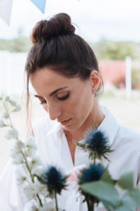 brunette woman wearing white shirt looking down at flowers