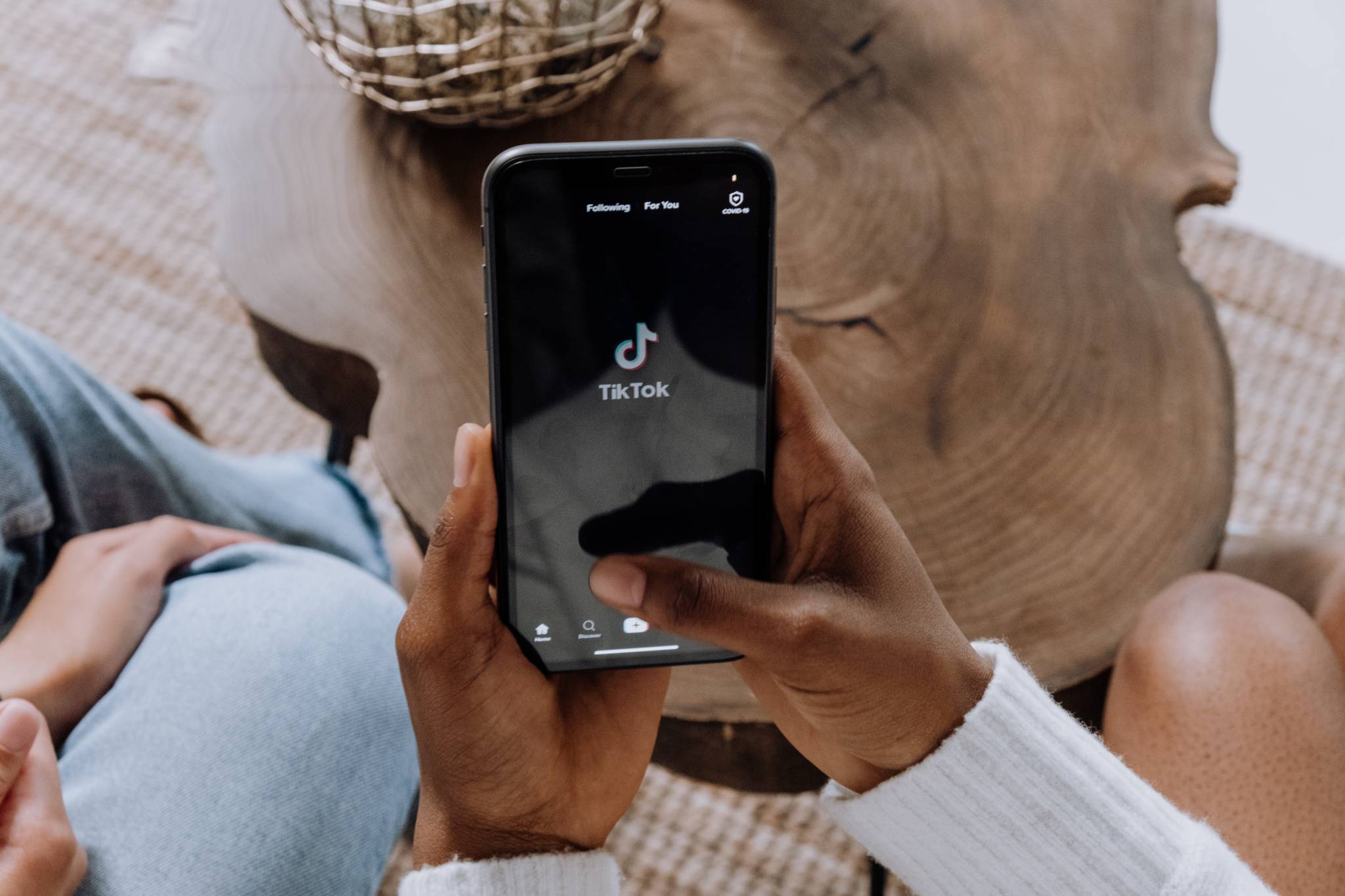 woman holding phone in hands with TikTok app launching logo showing