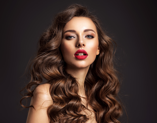 brunette woman in front of black background wearing red lipstick