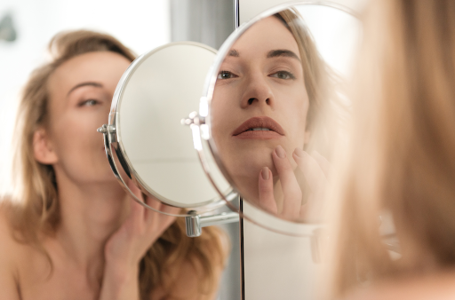 blond woman looking at reflection in circular mirror