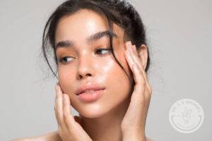 Portrait of young woman touching her face with her fingers