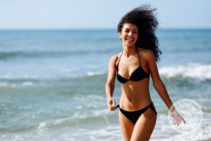 ethnic woman in bikini smiling while on the beach