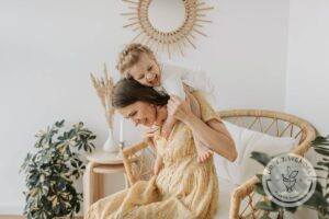 Laughing blonde baby sitting on the shoulders of mother