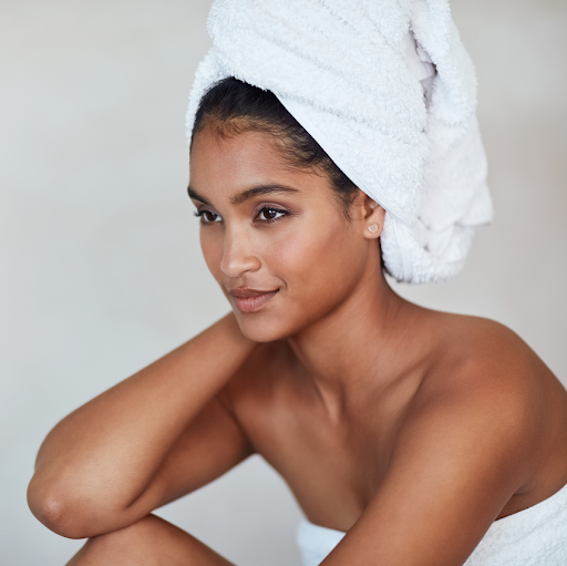 woman with hair wrapped in a bath towel gazes to the left