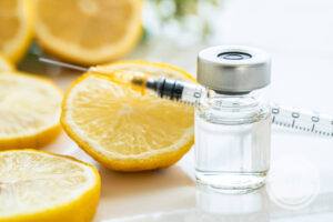 vitamin injection and syringe needle in front of sliced up lemons