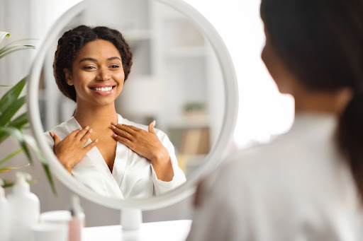 woman wearing robe smiling and looking at her reflection in the mirror