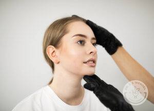 Person in black gloves touching the face of a young woman