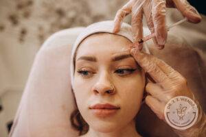Portrait of young Caucasian woman getting botox cosmetic injection in forehead.